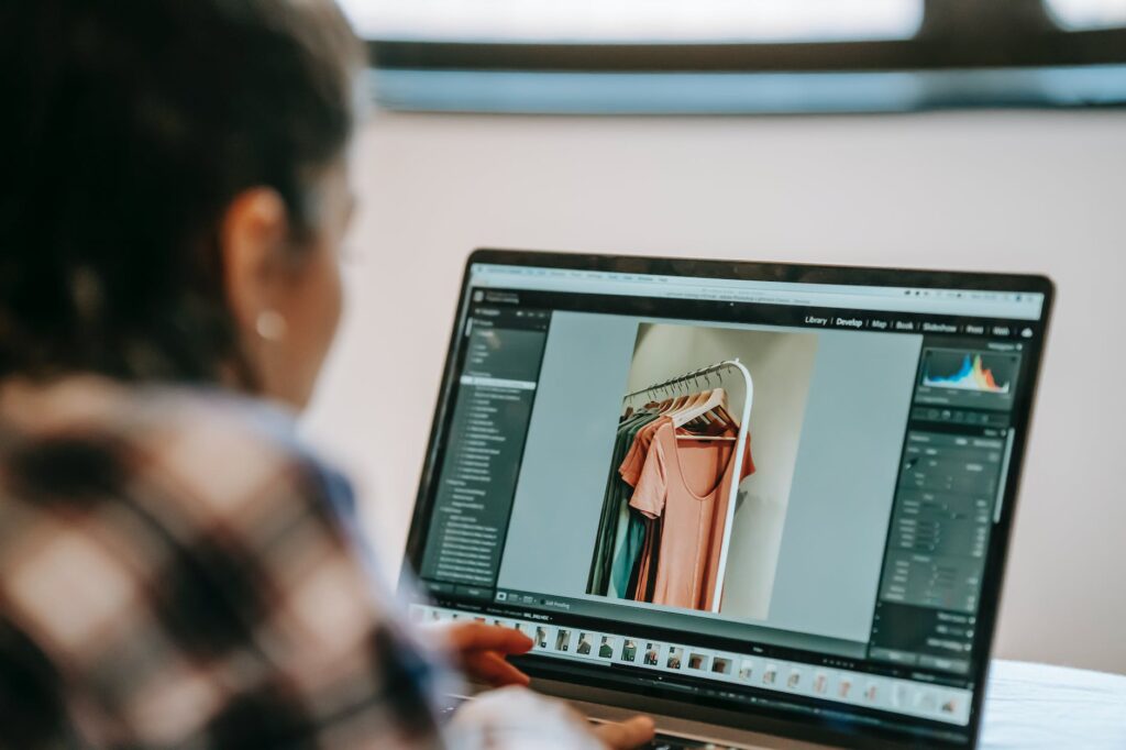 crop ethnic remote worker retouching photography on laptop at home