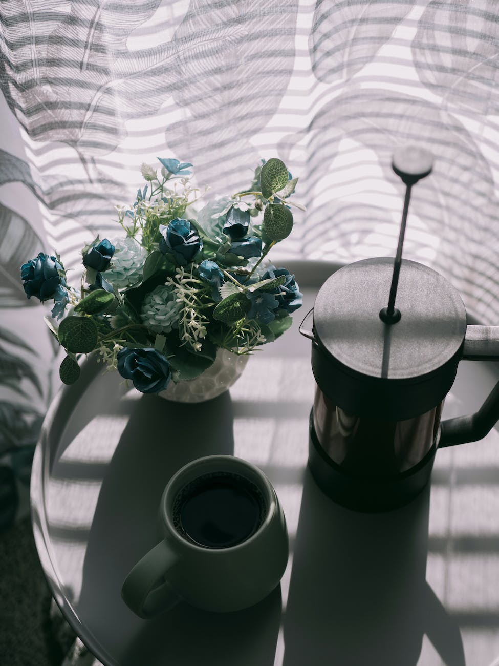a coffee coffee pot and a potted flower on the table