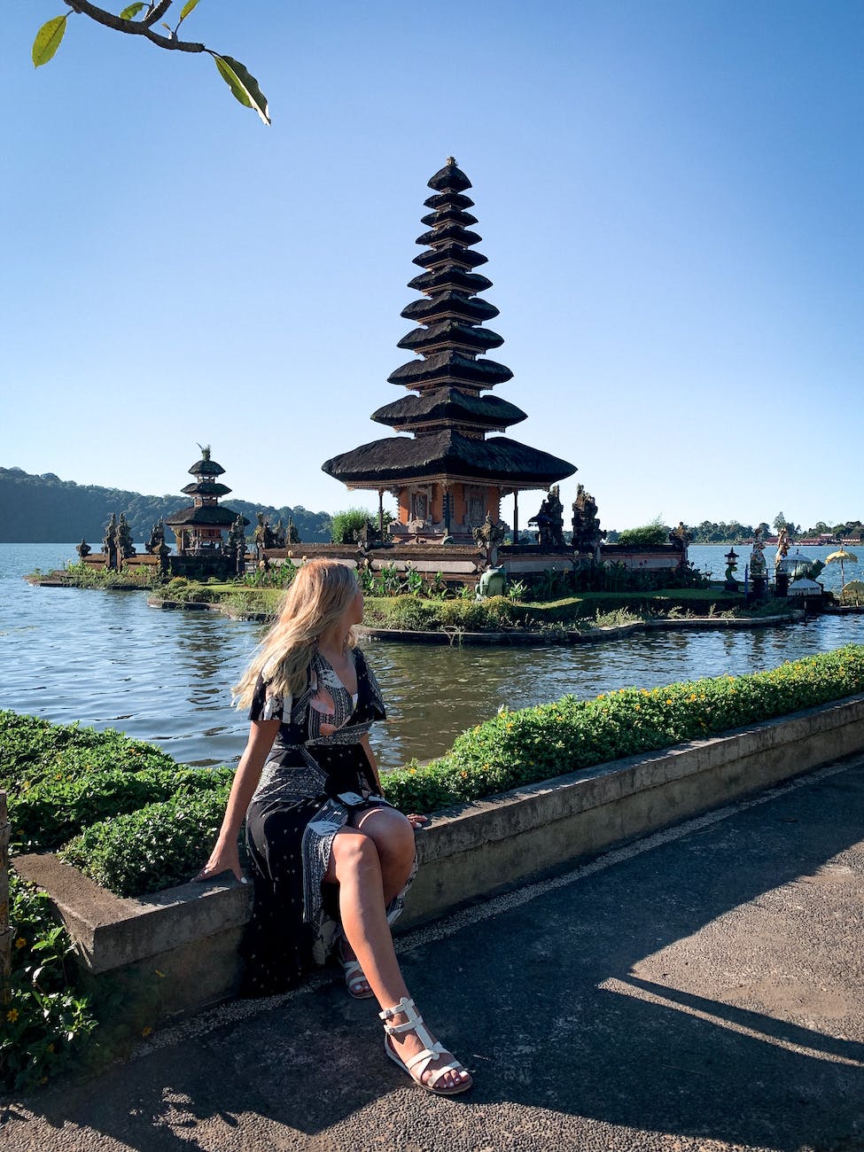 photo of woman sitting near plants looking at pagoda