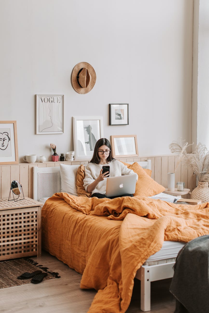 woman with laptop and smartphone on bed