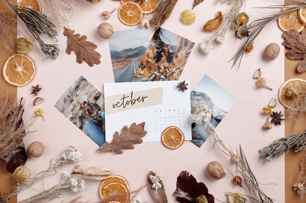 printed photos and october calendar paper surrounded by dried plants and flowers