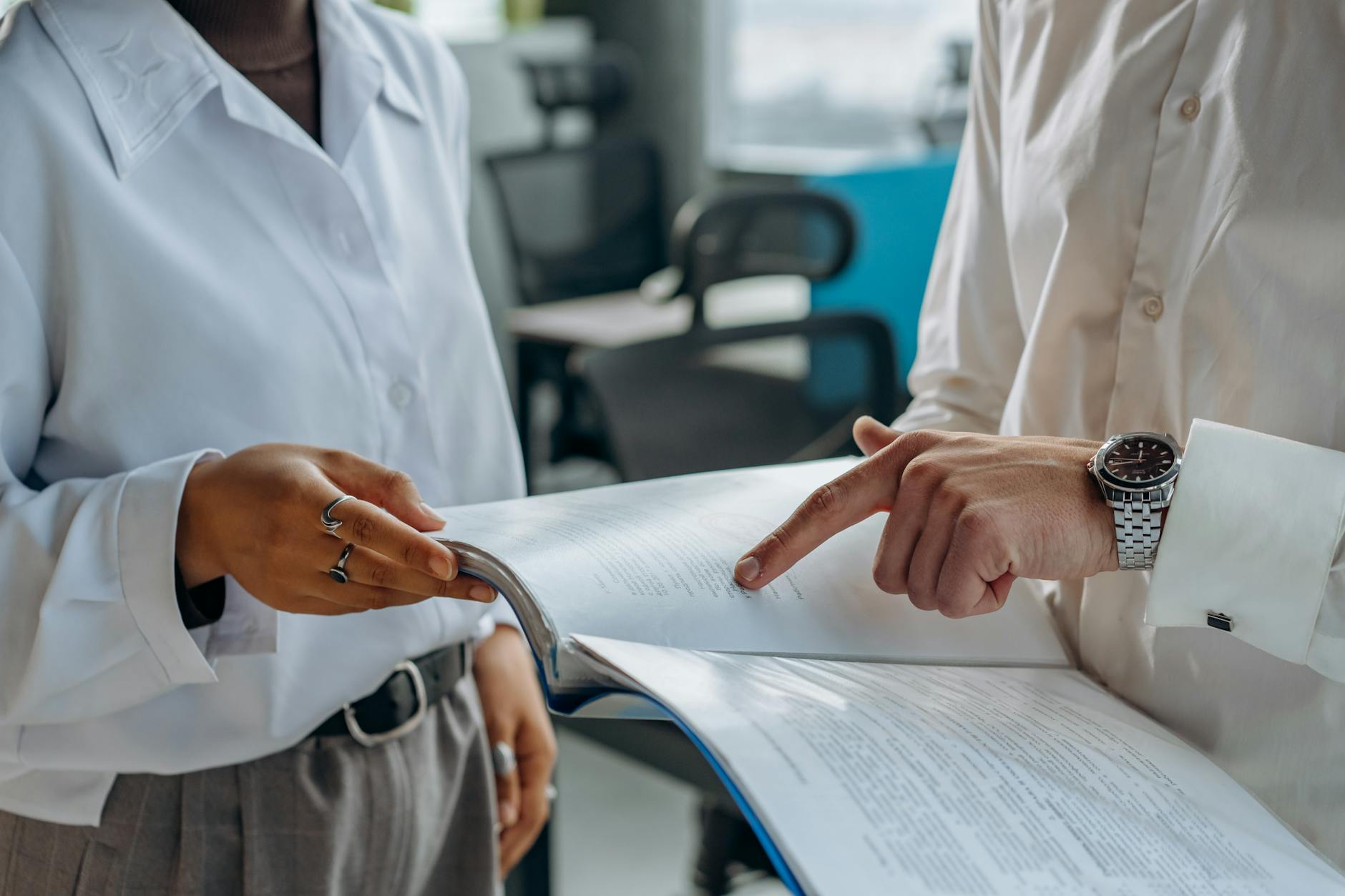 Apa Itu Jurusan Manajemen? Panduan Lengkap untuk Generasi Z 2 colleagues standing in white long sleeve shirts discussing and reading a financial report